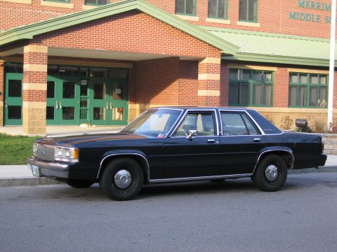 1991 Ford LTD Crown Victoria - A black 1991 Ford Crown Victoria LTD sedan is parked on a street in front of a brick building.