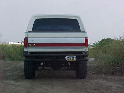 1990 Ford Bronco - Rear view of a white Ford Bronco with a red stripe and an aftermarket bumper.