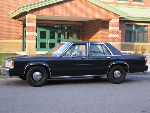 1991 Ford LTD Crown Victoria - Side profile of a 1991 Ford Crown Victoria LTD parked on asphalt in front of a brick building.