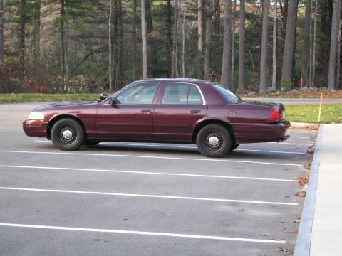 1991 Ford LTD Crown Victoria - A maroon sedan, likely from the early 2000s, is parked in a lot with trees in the background.