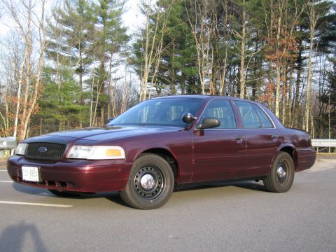1991 Ford LTD Crown Victoria - Maroon Ford Crown Victoria Police Interceptor with steel wheels and a lightbar mount on the driver's side mirror.