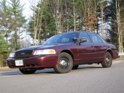 1991 Ford LTD Crown Victoria - A maroon 1991 Ford Crown Victoria is parked on the side of a road, with trees visible behind it.