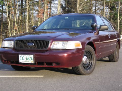 1991 Ford LTD Crown Victoria - A maroon Ford Crown Victoria sedan is parked on asphalt with trees in the background.