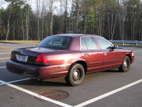 1991 Ford LTD Crown Victoria - A red Ford Crown Victoria is parked in a lot, showing its rear 3/4 view with a license plate visible.