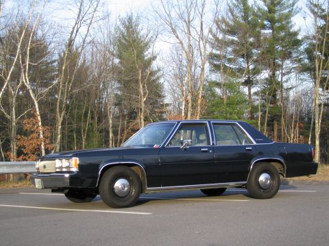 1991 Ford LTD Crown Victoria - This 1991 Ford Crown Victoria LTD is seen from the side, parked on a road with trees in the background.