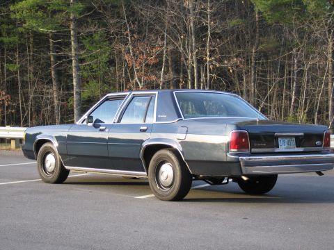 1991 Ford LTD Crown Victoria - Rear view of a 1991 Ford Crown Victoria LTD, parked outdoors with trees in the background.
