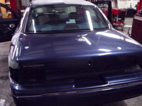 1996 Ford Crown Victoria - Rear view of a dark blue sedan with doors open, possibly undergoing refinishing.