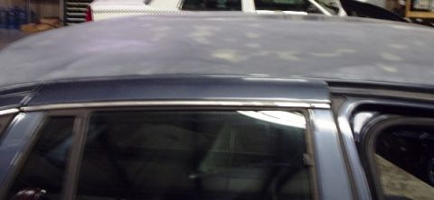 1996 Ford Crown Victoria - The roof of a car is covered in primer, with another vehicle partially visible in the background.