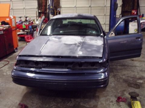 1996 Ford Crown Victoria - A blue sedan sits in a garage with its hood open and doors ajar, appearing to be in the process of refinishing.
