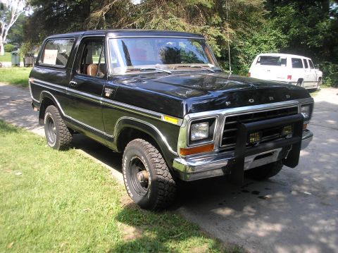 1978 Ford Bronco - This 1978 Ford Bronco is presented in black with chrome accents and a front bull bar. A white SUV is visible in the background.