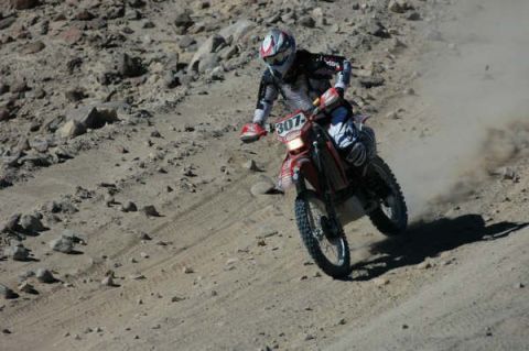 1990 Ford Bronco - motocross racer wearing white gear rides red dirt bike number 307 down a dusty, rocky desert course.