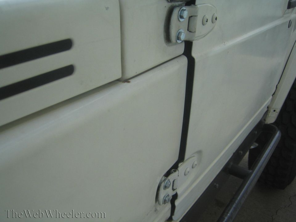 White 1987 Suzuki Samurai side door and hinges, with black trim and a step bar