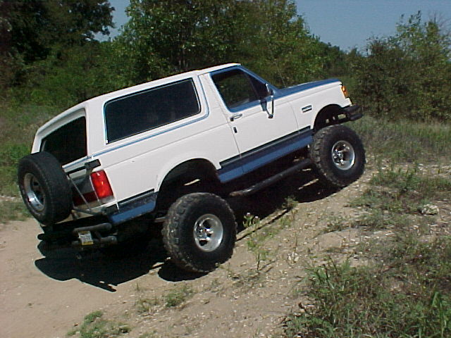 White and blue Ford Bronco, 3/4 front view, with spare tire on rear
