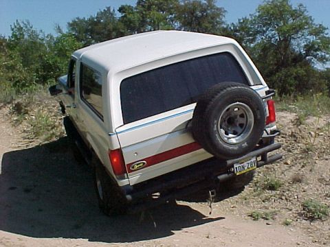 1990 Ford Bronco - This 1990 Ford Bronco is seen from the rear on a dirt road with trees in the background.
