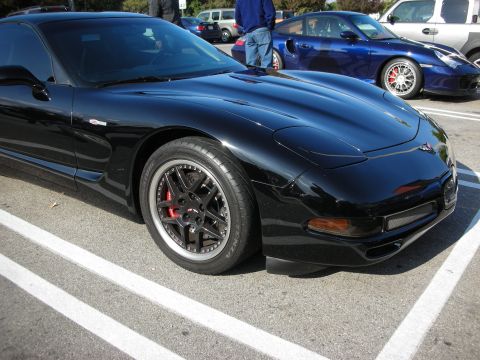 1998 Ford Crown Victoria - front fender and wheel of a black Corvette C5 with a red brake caliper, parked among other cars.