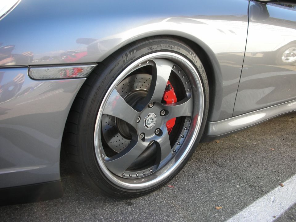 Close-up of silver Porsche front wheel, multi-spoke rim with red brake caliper