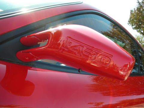 1998 Ford Crown Victoria - Close-up of a red Ferrari's body-colored side mirror with raised 430 lettering molded into the housing.