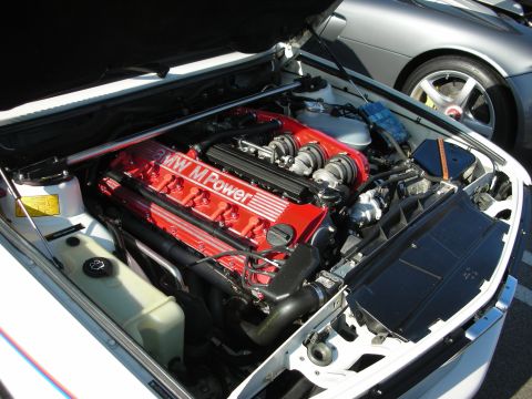 1998 Ford Crown Victoria - BMW M Power inline-six engine with a red valve cover and individual throttle bodies in an open engine bay.