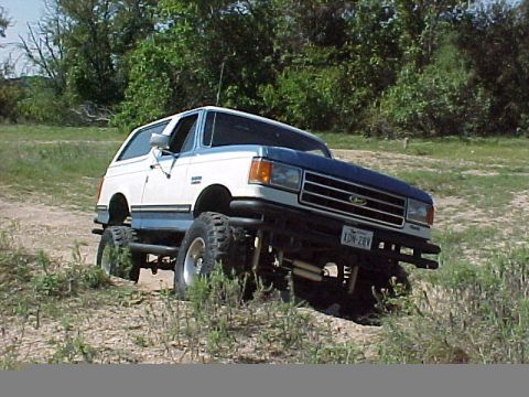 1990 Ford Bronco - This lifted 1990 Ford Bronco is shown off-roading in a grassy, wooded area. The license plate reads XON-28V.