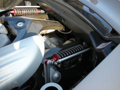 1998 Ford Crown Victoria - Close-up of red-spring coilover shock absorbers and suspension components inside a silver car's engine bay.