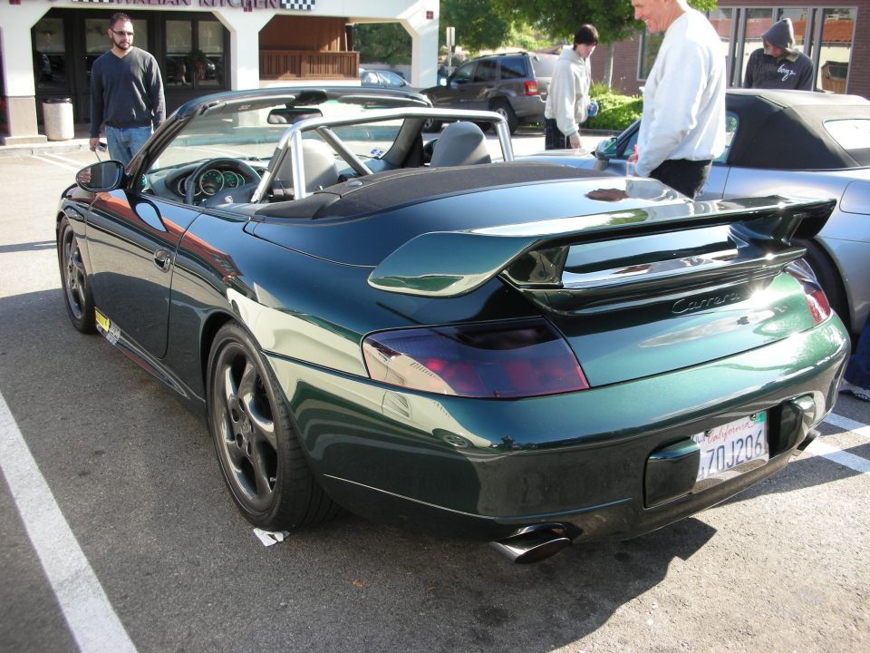 Dark green Porsche 996 Carrera cabriolet with raised rear spoiler at a car show