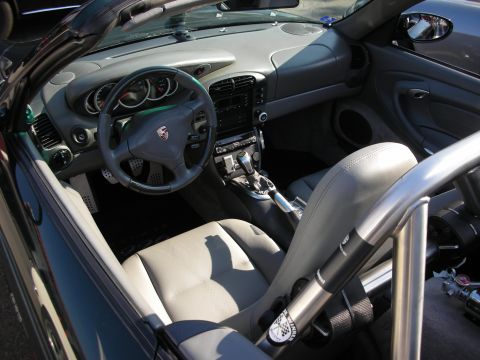 1998 Ford Crown Victoria - two-tone interior of a Porsche 996 shows its crested steering wheel, manual shifter, gray seats and a roll bar.