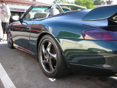 1998 Ford Crown Victoria - close rear three-quarter view of a dark green Porsche 996 highlights its glossy paint and dark multi-spoke wheel.