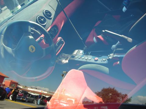 1998 Ford Crown Victoria - Shot through the windshield, a Ferrari interior shows a red-and-black cabin, prancing-horse steering wheel and gated metal shifter.
