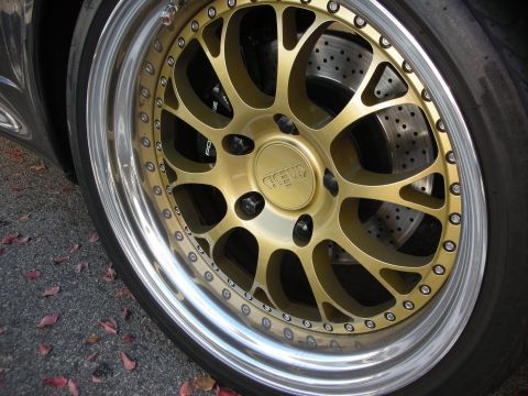 1998 Ford Crown Victoria - close-up of a gold mesh wheel with a polished lip shows a CCW center cap and a cross-drilled brake rotor behind the spokes.