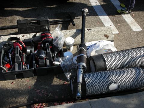 1998 Ford Crown Victoria - toolbox, red power tools, a coffee cup and assorted parts are spread out on the pavement near a vehicle at a car meet.