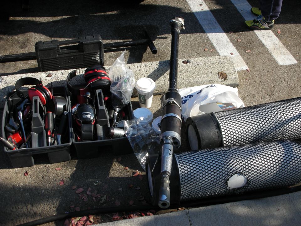 Toolbox, power tools, coffee cup and parts laid out on pavement at a car show