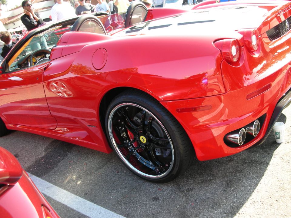 Rear quarter of a red Ferrari F430 Spider convertible with black chrome-lip wheels at a car meet