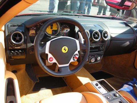 1998 Ford Crown Victoria - Cockpit of a Ferrari with tan leather seats, carbon-look trim, a yellow-faced tachometer, and the prancing-horse badge on the steering whee…