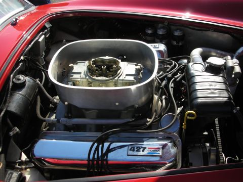 1998 Ford Crown Victoria - Engine bay of a Cobra showing a four-barrel carburetor and chrome valve covers stamped '427 Cobra' on a red-bodied car.