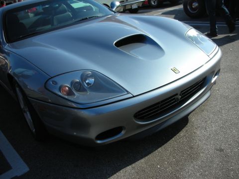 1998 Ford Crown Victoria - Front close-up of a silver Ferrari front-engine V12 coupe showing the hood scoop, yellow prancing-horse badge, and open grille.