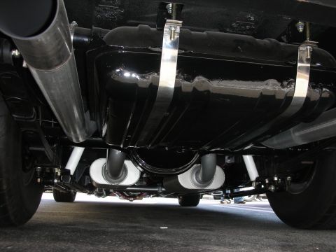 1998 Ford Crown Victoria - Undercarriage detail showing a glossy black fuel tank, twin polished bullet mufflers, and chrome exhaust piping.