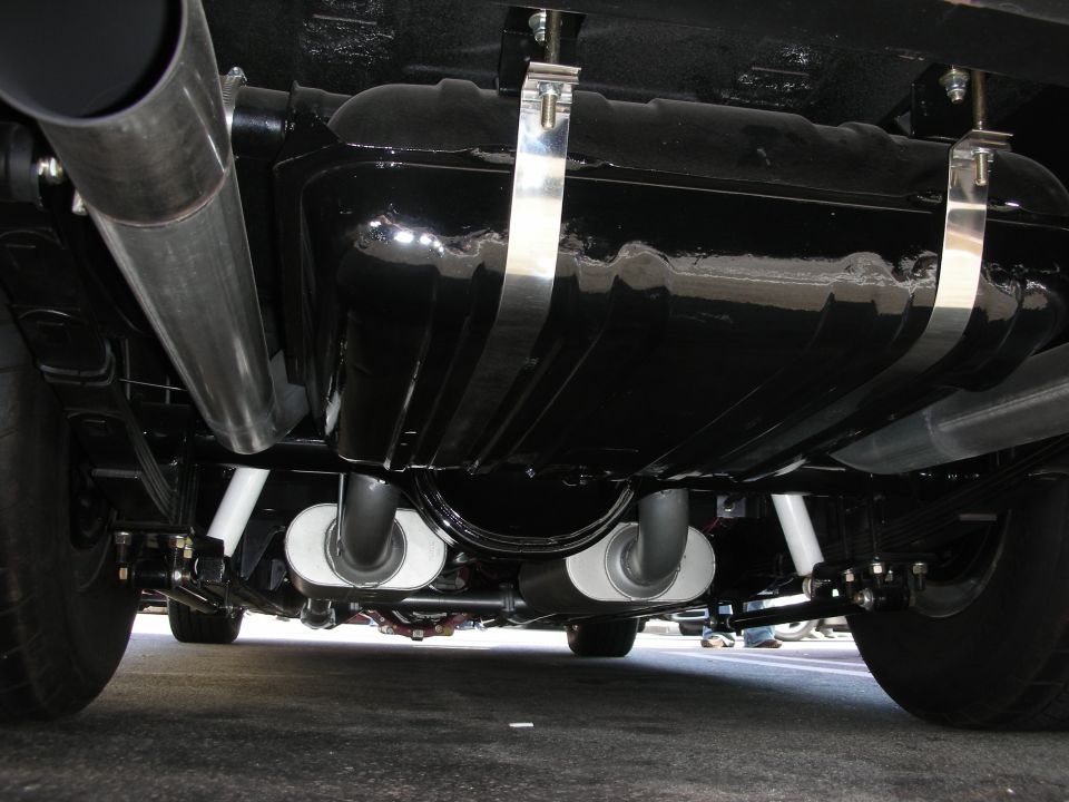 Underside view of a black fuel tank, polished mufflers, and dual exhaust
