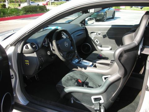 1998 Ford Crown Victoria - Driver-side interior of a silver Mercedes AMG coupe showing carbon-look trim, flat-bottom wheel, and Alcantara sport bucket seats.