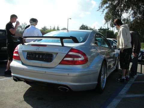 1998 Ford Crown Victoria - Rear view of a silver Mercedes-Benz CLK DTM AMG coupe with a wide body, tall rear wing, and dual exhaust as onlookers stand nearby.