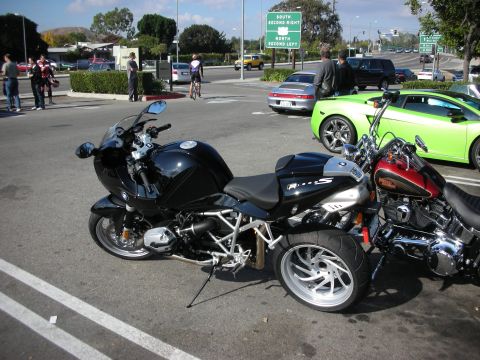 1998 Ford Crown Victoria - black BMW R1200S sport motorcycle parked next to a maroon Harley-Davidson, with a green Lamborghini and street sign in the background.