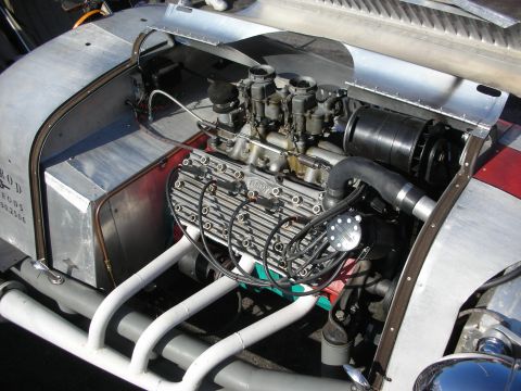 1998 Ford Crown Victoria - Engine bay of a hot rod showing a polished V8 with twin carburetors, finned valve covers and swept exhaust headers.