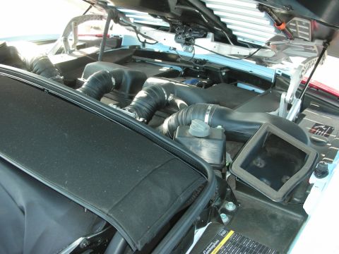 1998 Ford Crown Victoria - View under the hood of a white car showing the black air intake tubing and airbox of the engine bay.