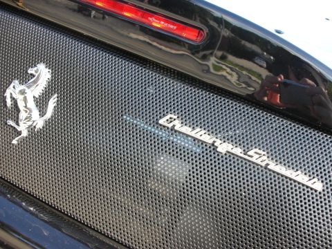 1998 Ford Crown Victoria - Close-up of a Ferrari prancing-horse emblem and Challenge Stradale script on the black mesh engine cover of a sports car.