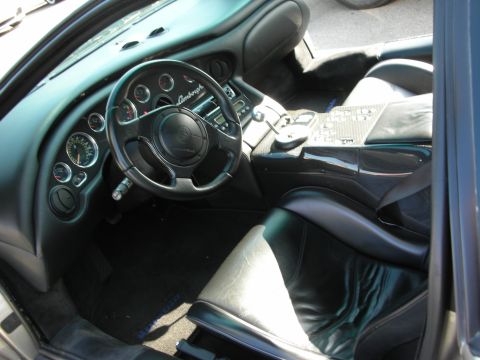 1998 Ford Crown Victoria - Interior of a Lamborghini showing black leather seats, a Lamborghini steering wheel and gated metal shifter.