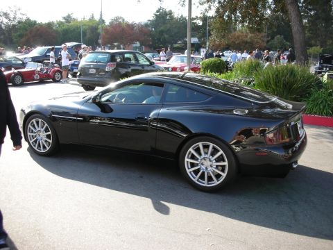 1998 Ford Crown Victoria - black Aston Martin Vanquish grand-touring coupe shown in profile with silver multi-spoke wheels at a car meet.