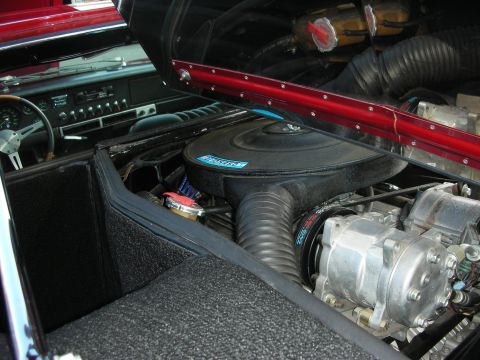 1998 Ford Crown Victoria - rear-mounted V8 with a large black air cleaner sits beside the carpeted cabin and dashboard of a classic car.