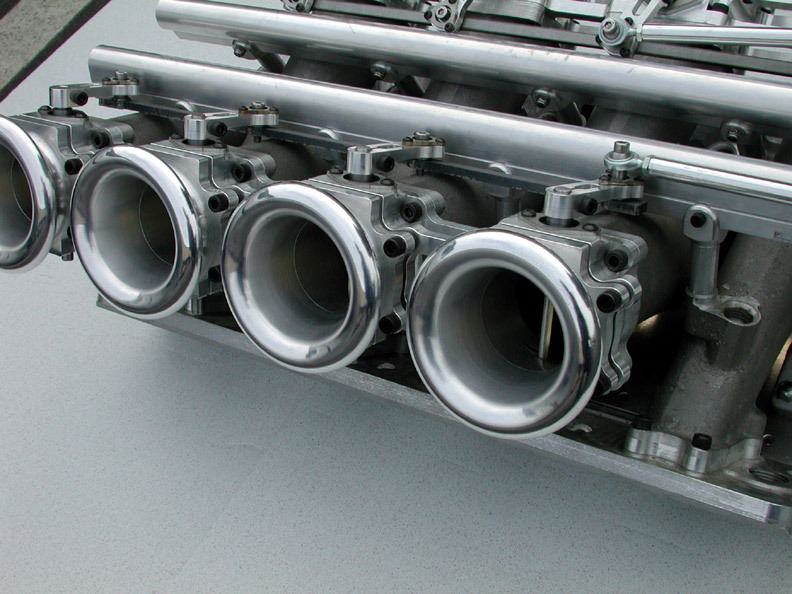 close-up of a performance intake manifold with four polished throttle bodies