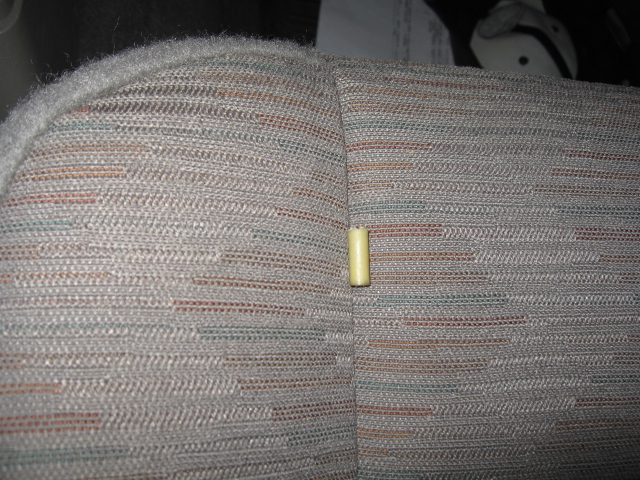 Close-up of patterned fabric on a vehicle seat with a small yellow cylinder