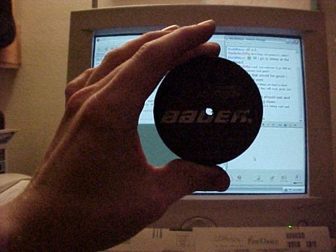 1990 Ford Bronco - A hand holds a Bauer hockey puck in front of a computer monitor displaying text.