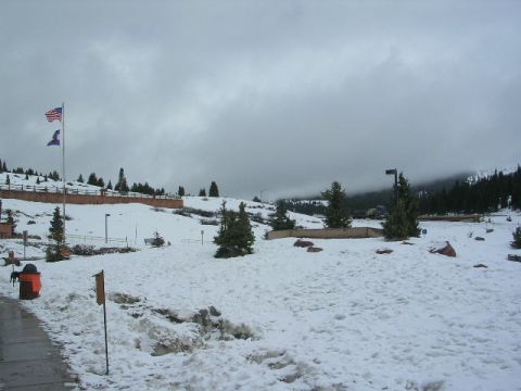 1975 Ford Ranchero - A winter scene with flags flying and snow covering the ground, with trees and hills in the background.